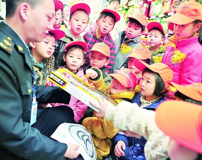3月14日，陕西省宁强县幼儿园的小朋友在该县质量技术监督局工作人员的指导下寻找食品的QS（质量安全）标识。黎德华摄/光明图片
