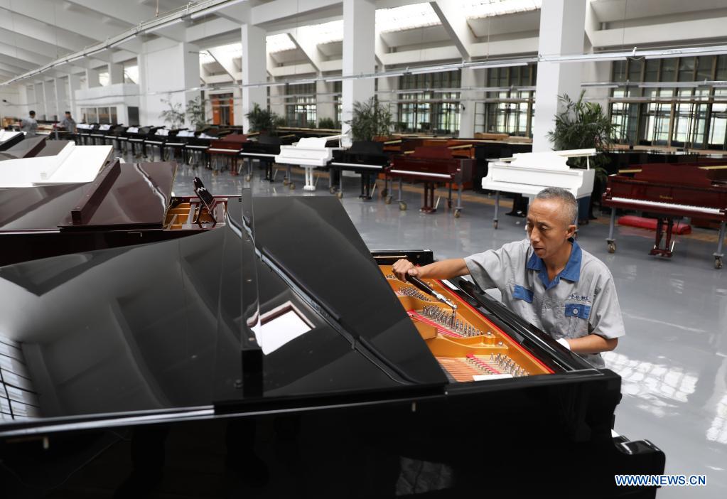 Workers make pianos at Dongbei Piano Factory in NE China