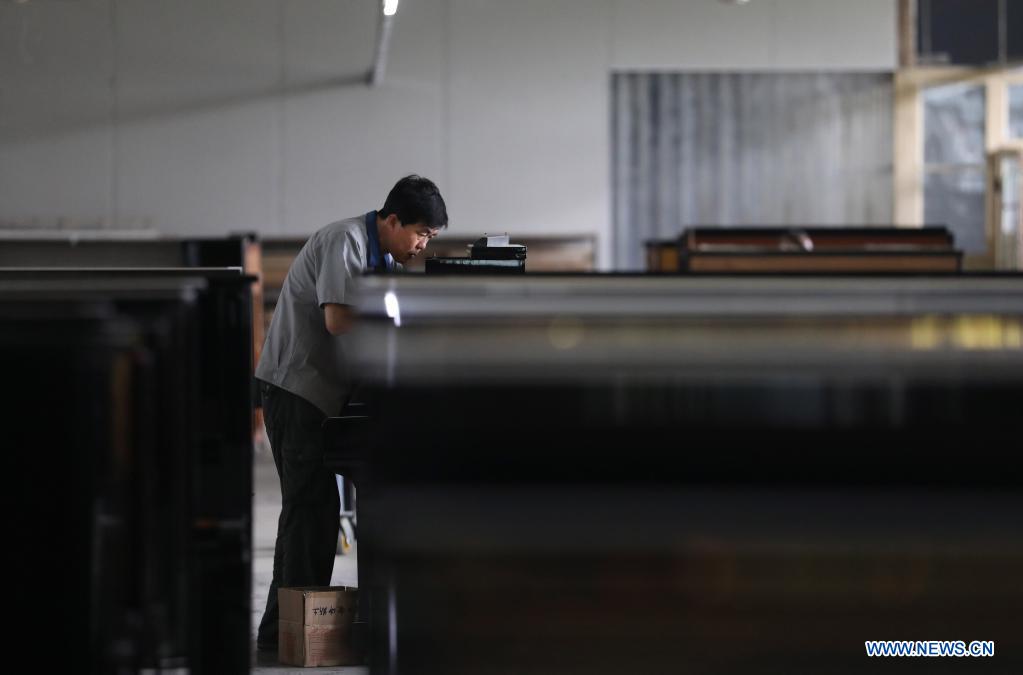 Workers make pianos at Dongbei Piano Factory in NE China