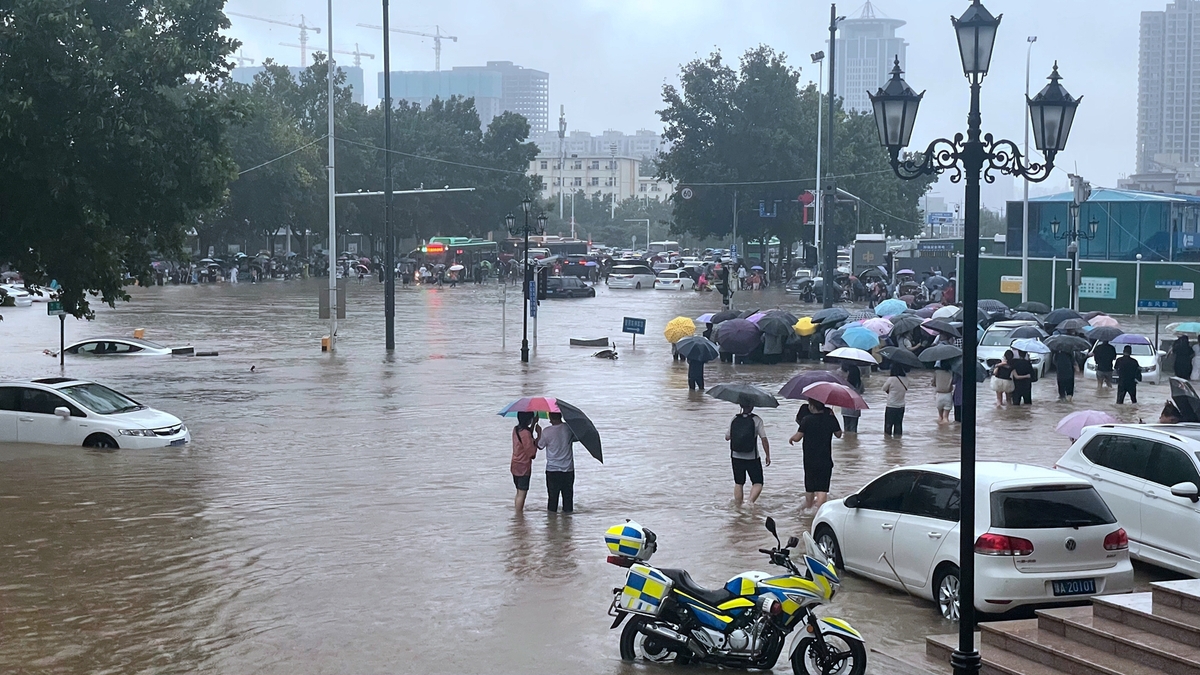 Police help people cross flooded roads in C China's Zhengzhou