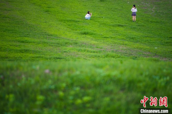 重庆万州，民众在长江消落带草坪上留影拍照。　侯本艳 　摄