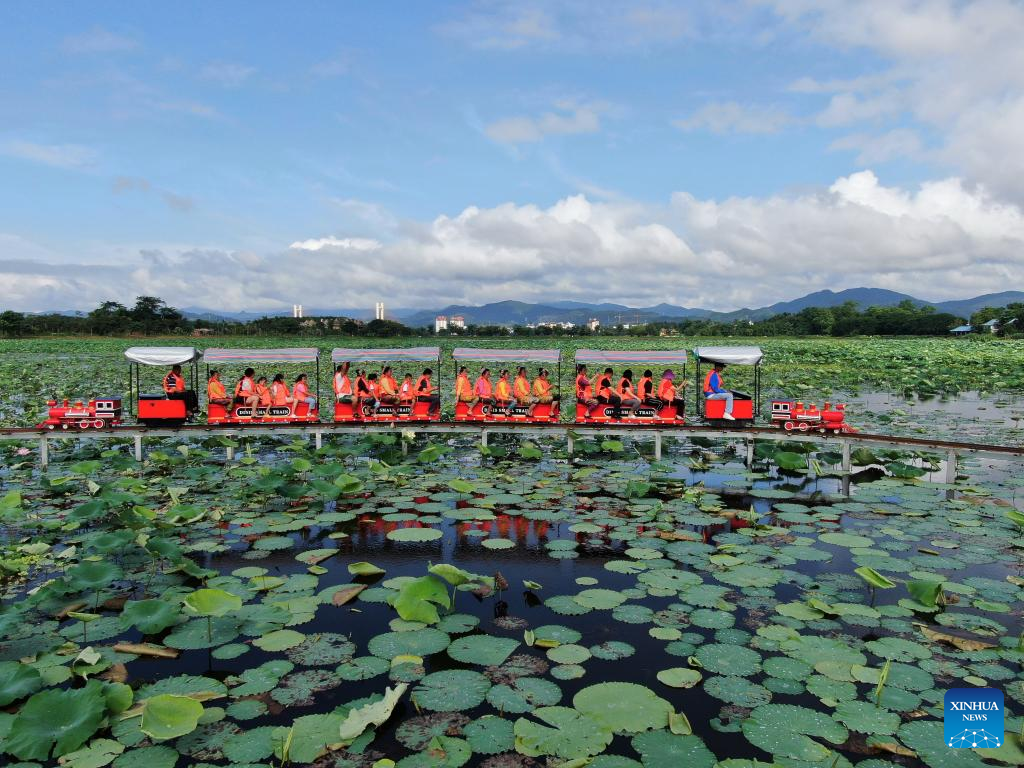 People enjoy lotus flowers at Longde Lake in Jinghong, Yunnan