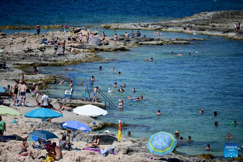 People cool off at St. Paul's Bay in Qawra, Malta