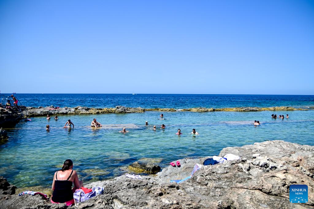 People cool off at St. Paul's Bay in Qawra, Malta