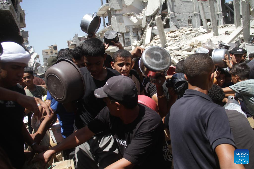 People gather to receive food relief in Jabalia refugee camp in Gaza Strip