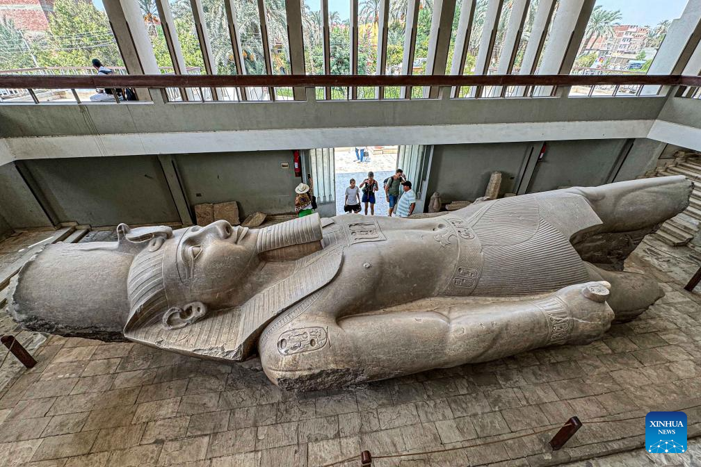 Tourists look at statue of ancient Egyptian king at Mit Rahina Museum