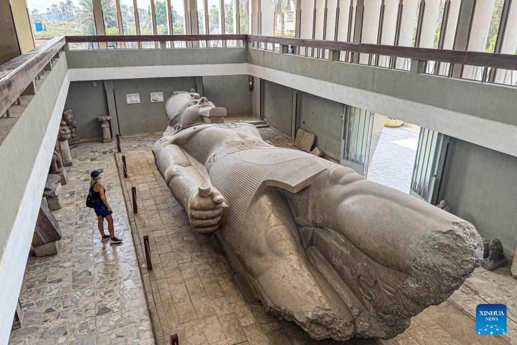 Tourists look at statue of ancient Egyptian king at Mit Rahina Museum