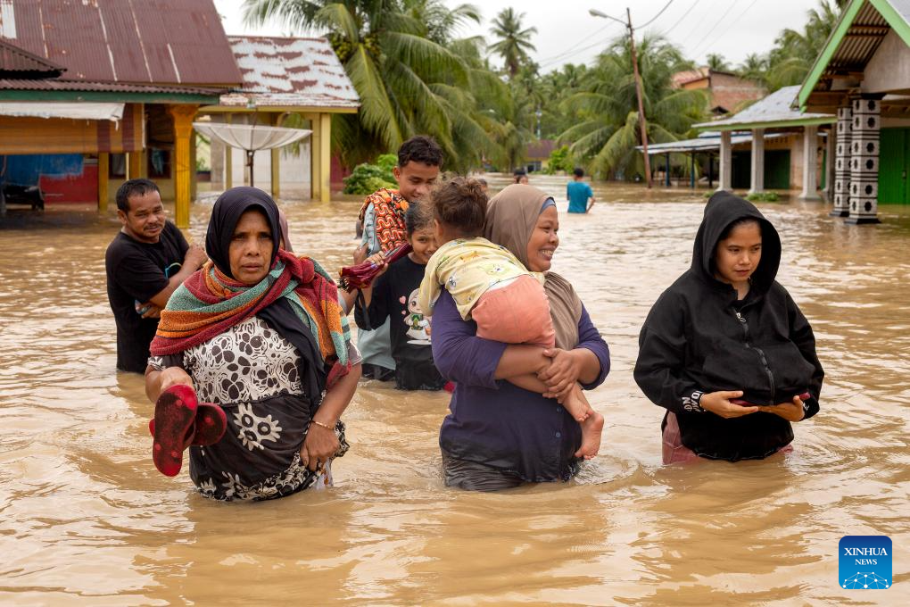 People wade through flood water in Padang Pariaman regency, Indonesia